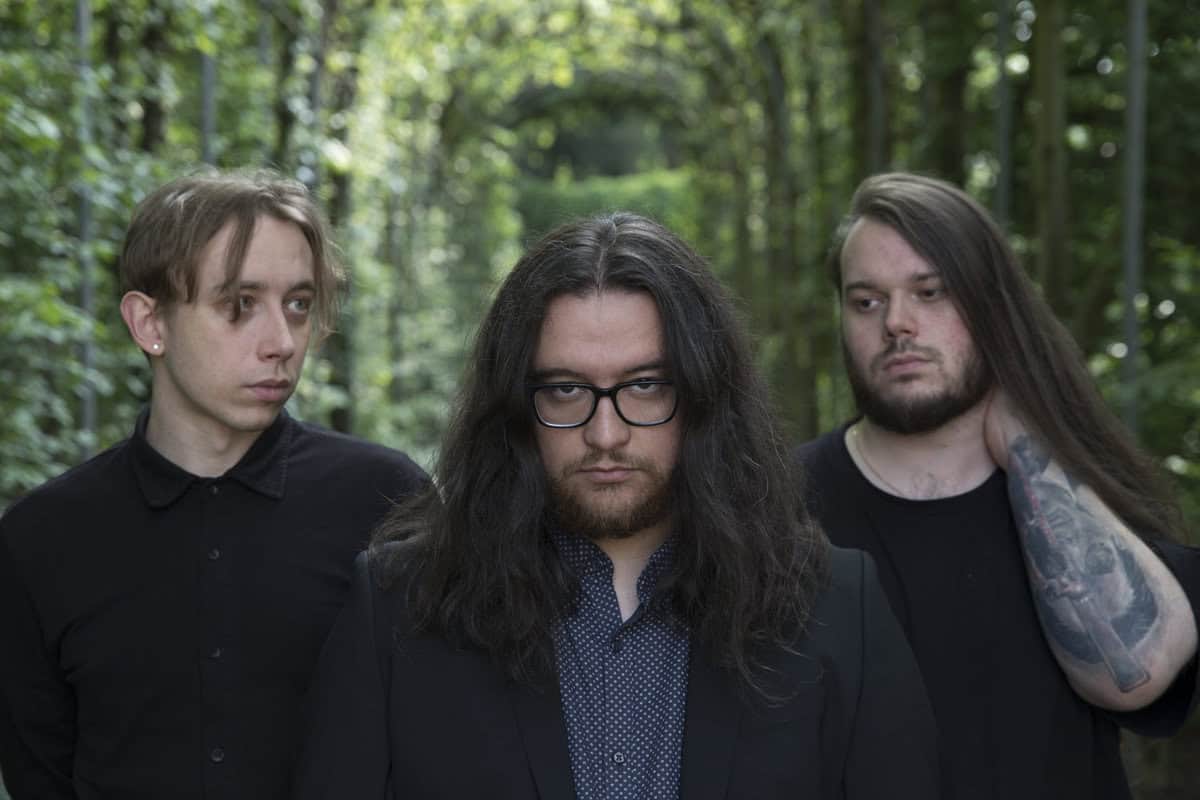 Dark-haired band members in a forest setting for MetalWar.gr.
