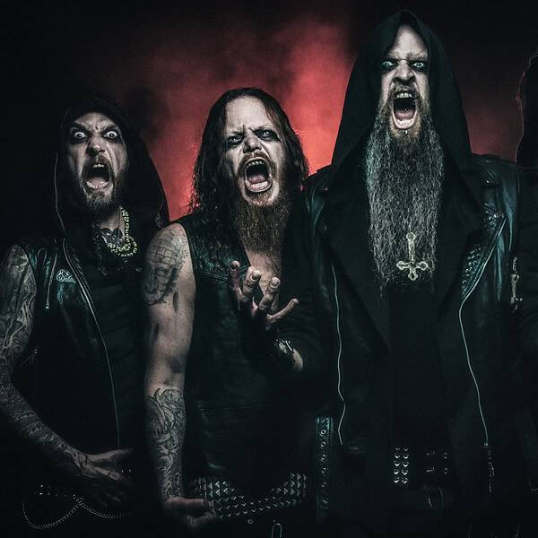 Four male metal musicians in black leather jackets scream toward the camera in a dark, moody setting.