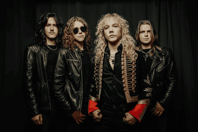 Four male rock musicians pose together in black leather jackets; one in the center wears a gold-embellished jacket with red cuffs, creating a dramatic stage look.