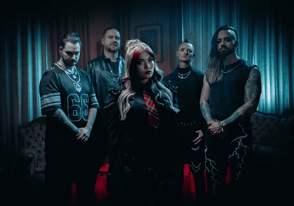 Five-member rock band in a moody blue/red-lit room; woman with blonde hair stands center front, others behind.