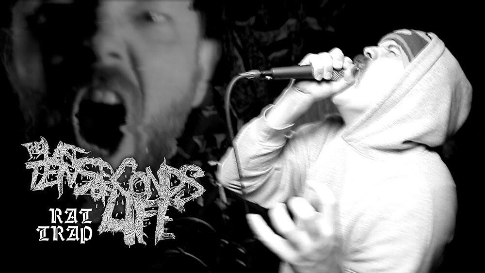 Black-and-white photo of a vocalist in a hoodie screaming into a microphone on stage, with a stylized band logo on the left.