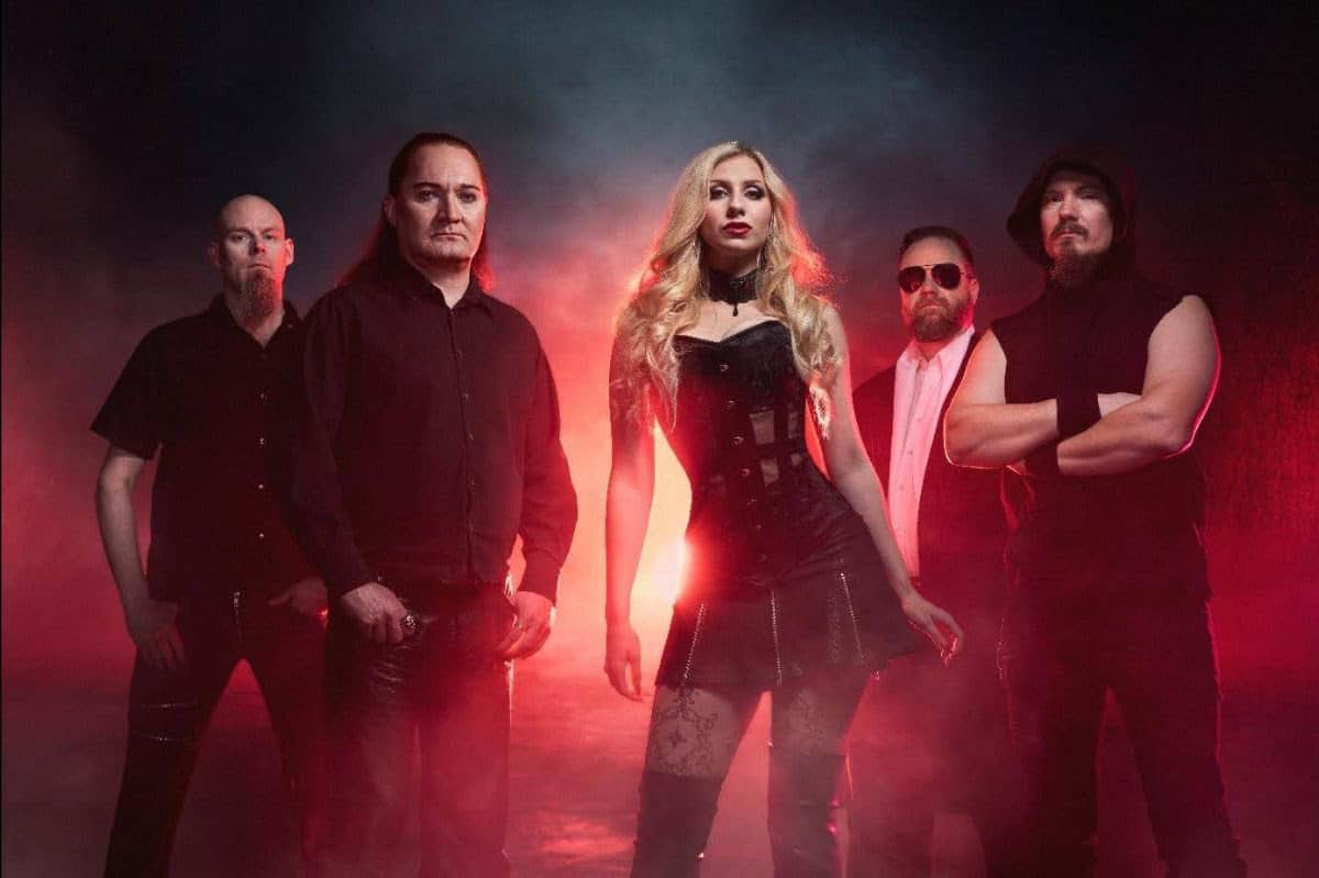 Female lead singer in a black corset dress stands center with four dark-clad bandmates amid red smoky lighting.
