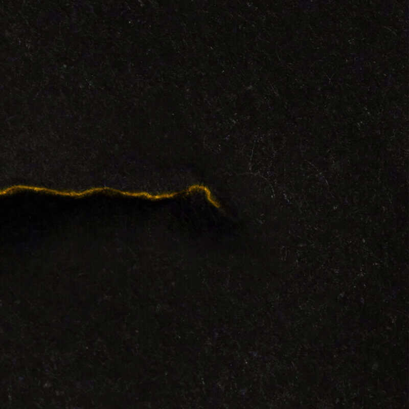 Dark granite surface with a thin, irregular yellow-orange line along the bottom edge