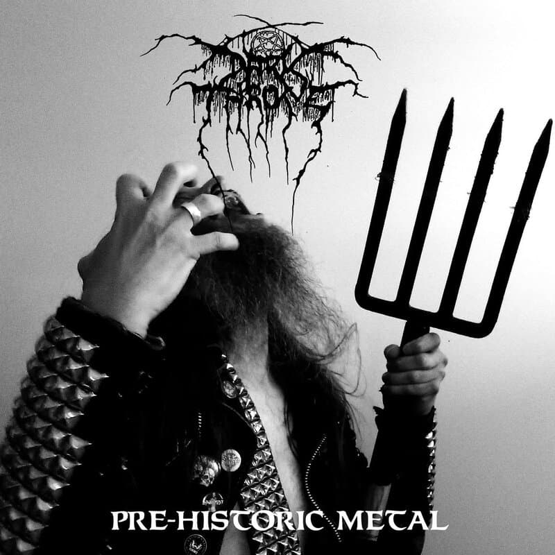 Black-and-white photo of a person with a spiked jacket pulling their hair, while holding a large pitchfork; the band-style logo and the text 'PRE-HISTORIC METAL' appear at the bottom.