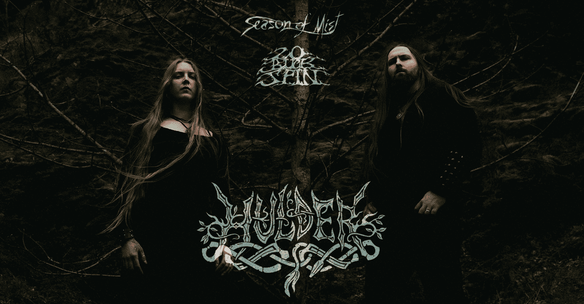 Promotional metal band photo: a man and a woman in black robes stand in a dim forest, with a stylized logo above and an ornate band logo below them (Season of Mist).