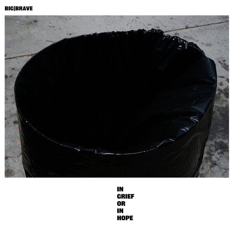 Top-down view of a black trash can with a liner on a concrete floor; album title 'IN GRIEF OR IN HOPE' at the bottom edge.