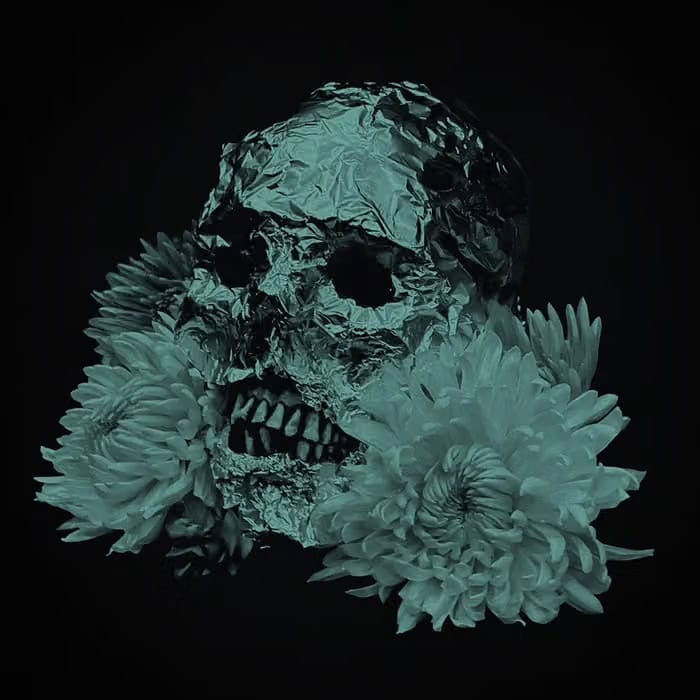 Teal-toned sculpture of a skull made from crumpled foil, surrounded by chrysanthemums against a black background.